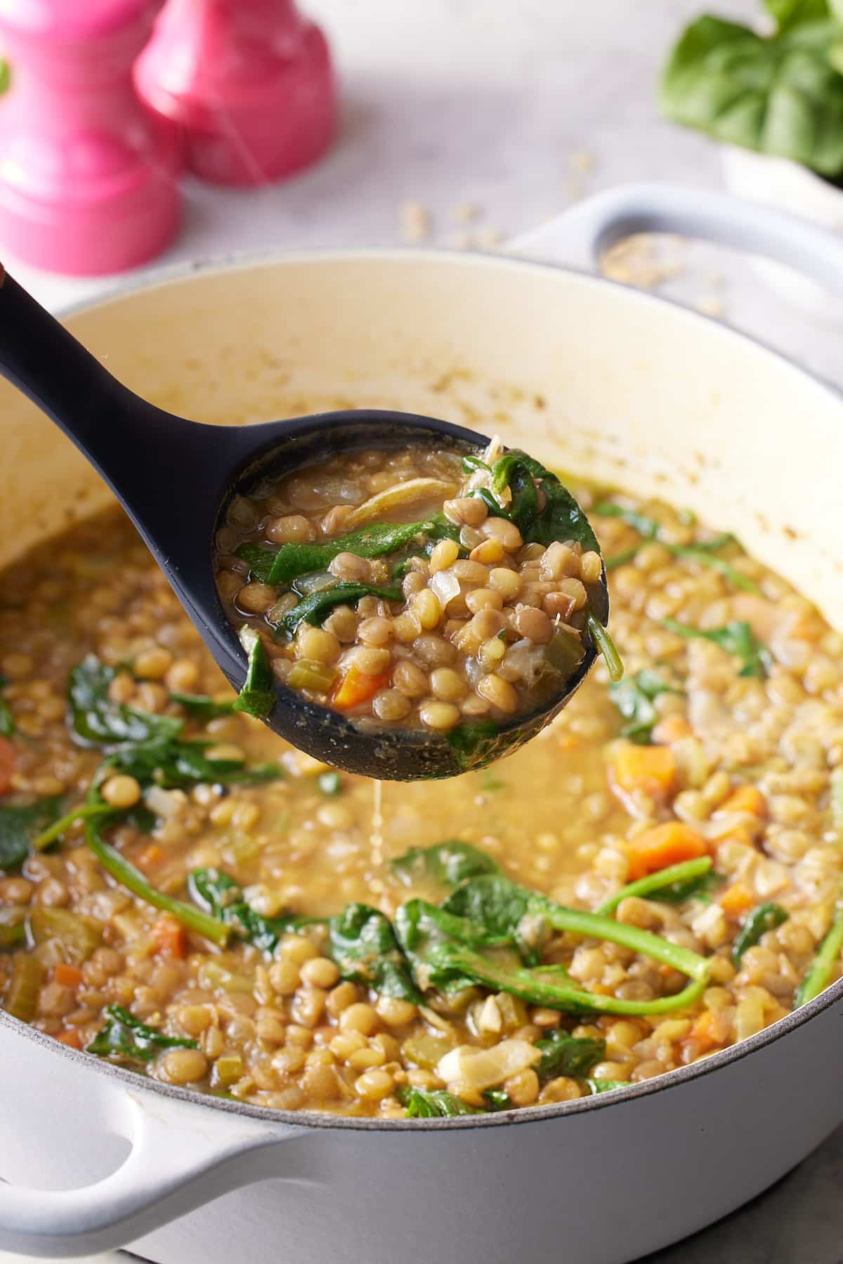 Lentil spinach soup being ladled out of the pot