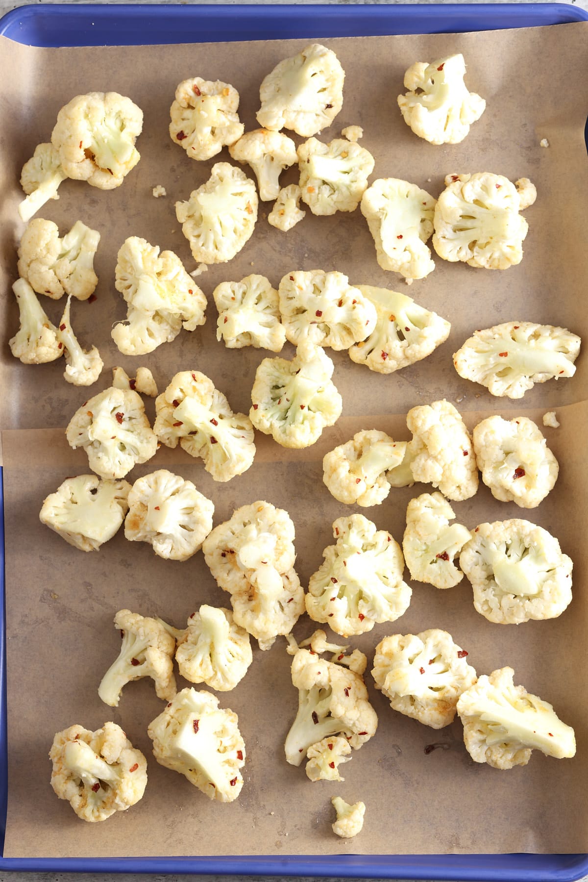 Seasoned cauliflower on a parchment lined baking sheet.