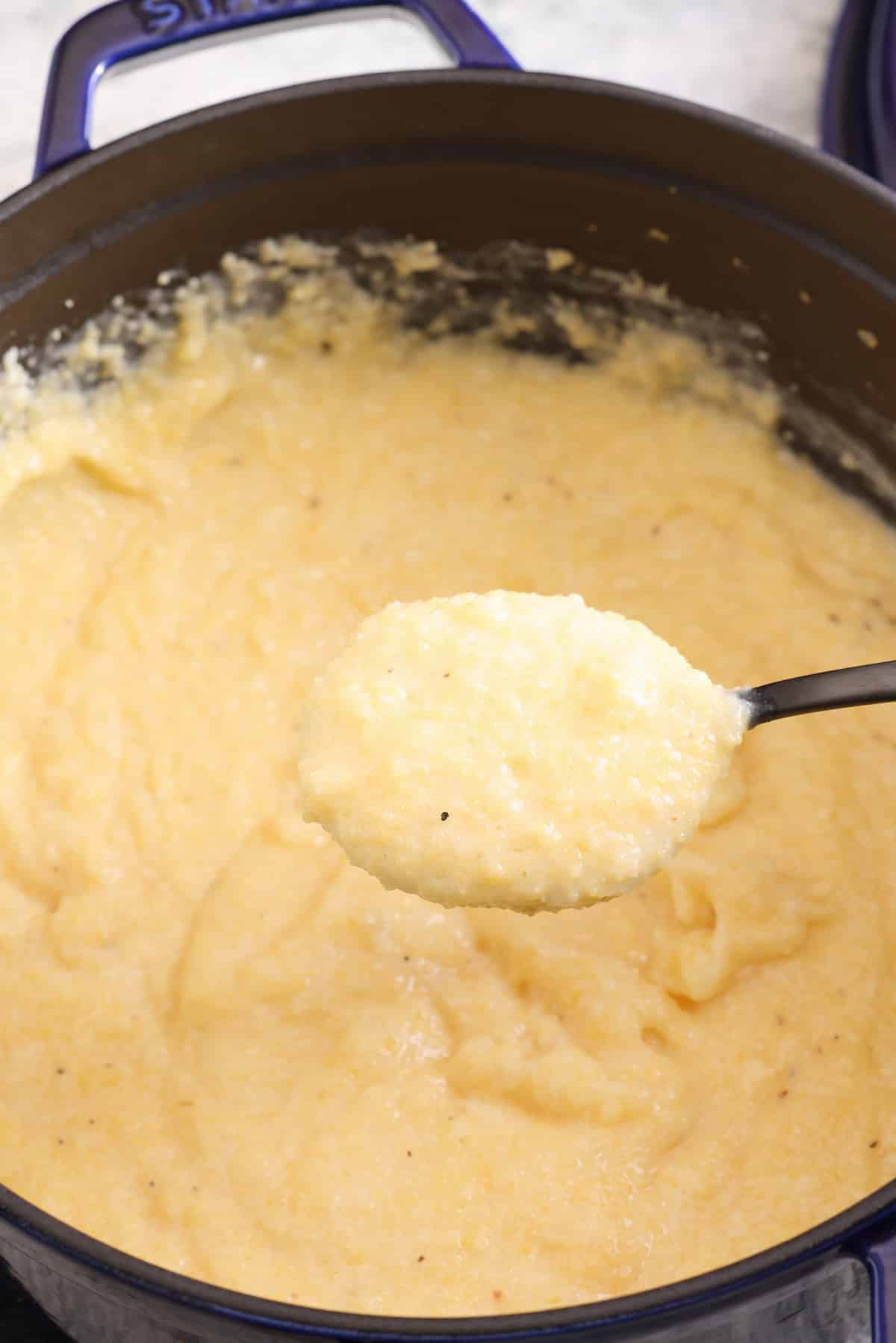 freshly cooked creamy polenta being stirred with a spoon. 