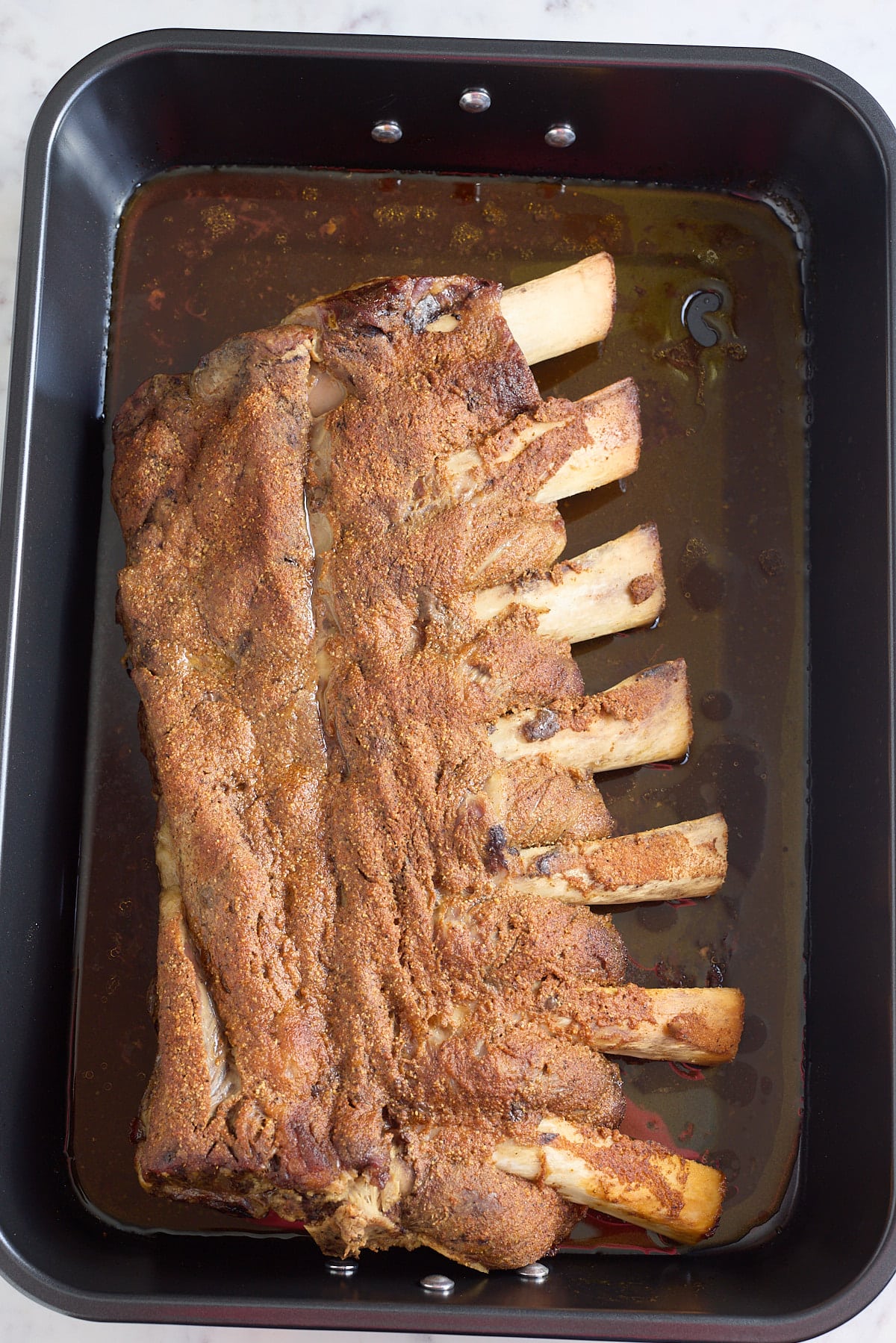 roasting pan with cooked beef ribs coated in bbq seasoning