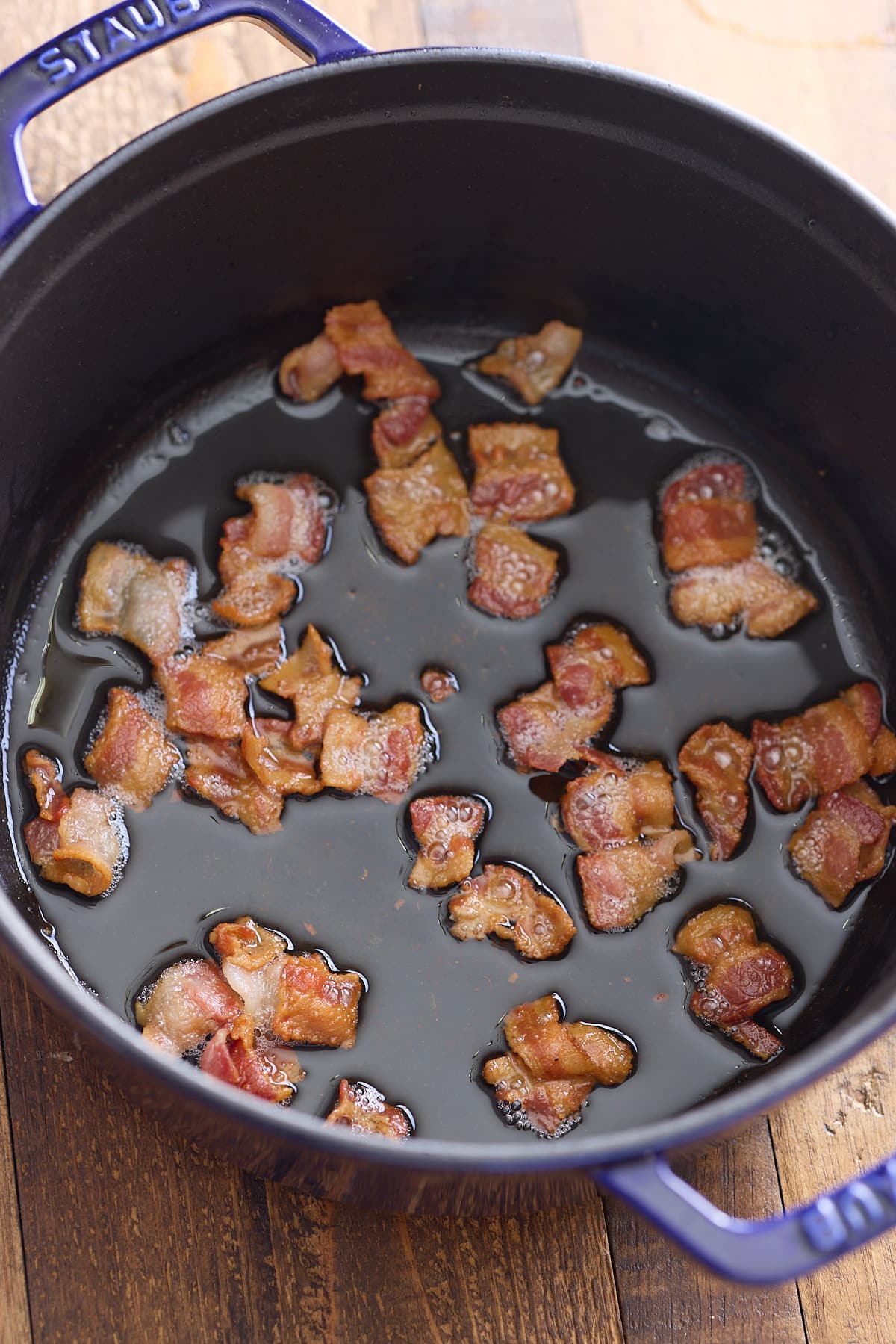 Bacon being fried in a dutch oven.