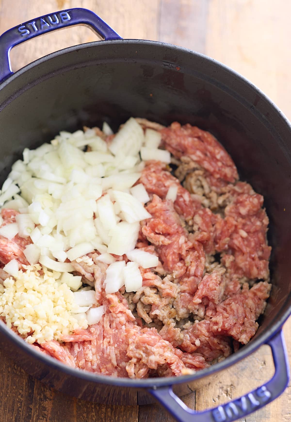 Sausage, onions, and garlic being cooked in the dutch oven.