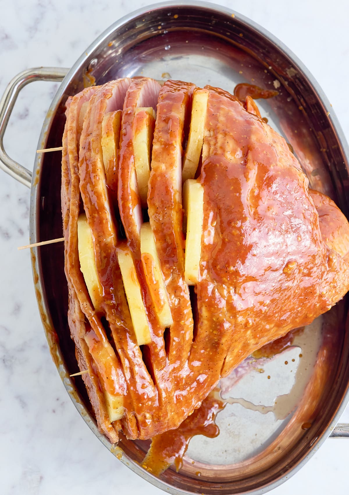 The spiral ham is added to the pot with slices of pineapple in the spirals.