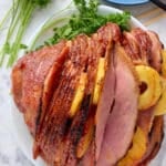 Fresh baked ham plated on a platter on the table.