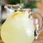 a pitcher filled with classic lemonade, topped with slices of fresh lemon