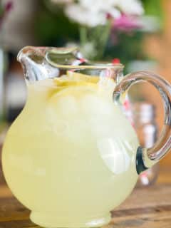 a pitcher filled with classic lemonade, topped with slices of fresh lemon