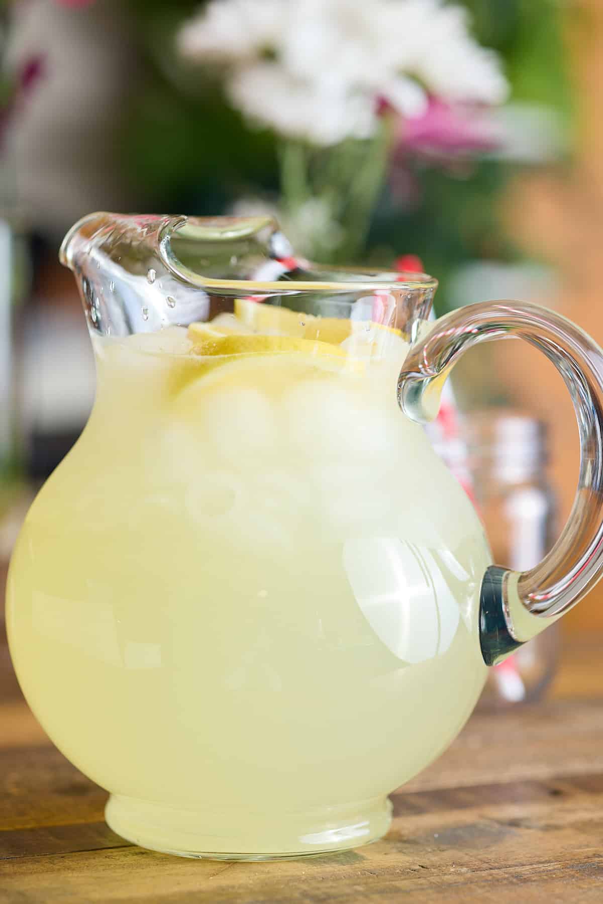 a pitcher filled with classic lemonade, topped with slices of fresh lemon