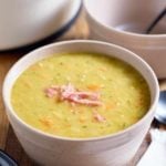 A bowl served with split pea soup topped with bits of ham.