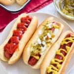 oven baked hot dogs in hot dog buns with a variety of toppings and sauces