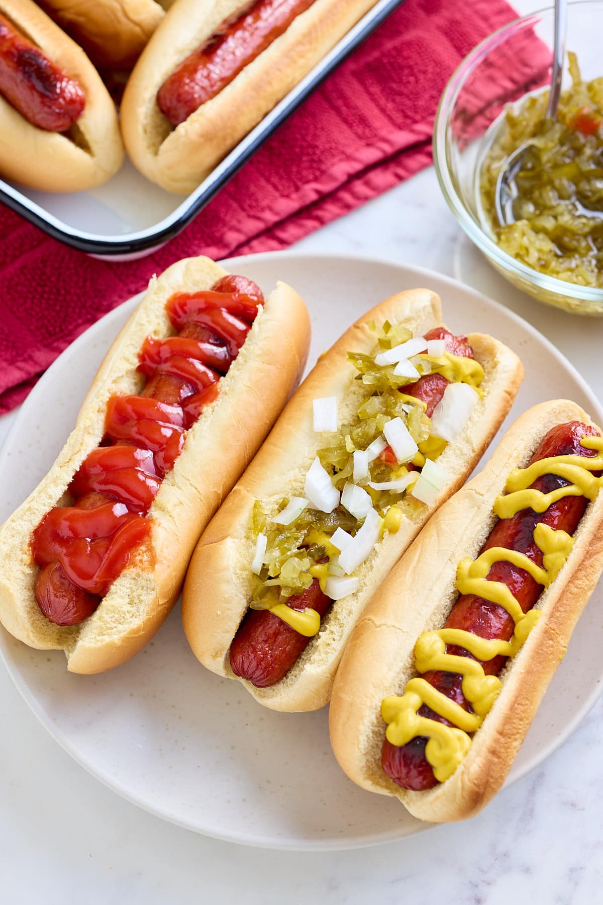oven baked hot dogs in hot dog buns with a variety of toppings and sauces