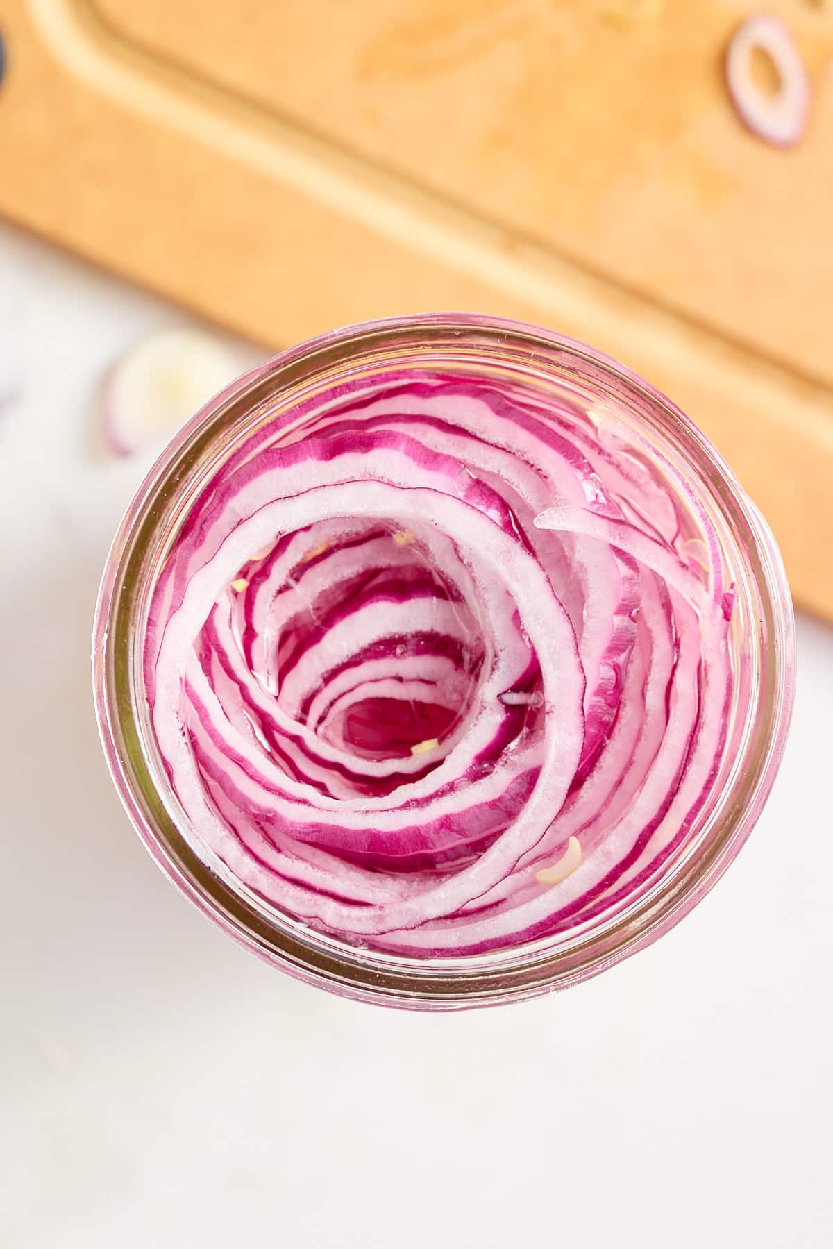 a jar filled with sliced red onions in a pickling liquid