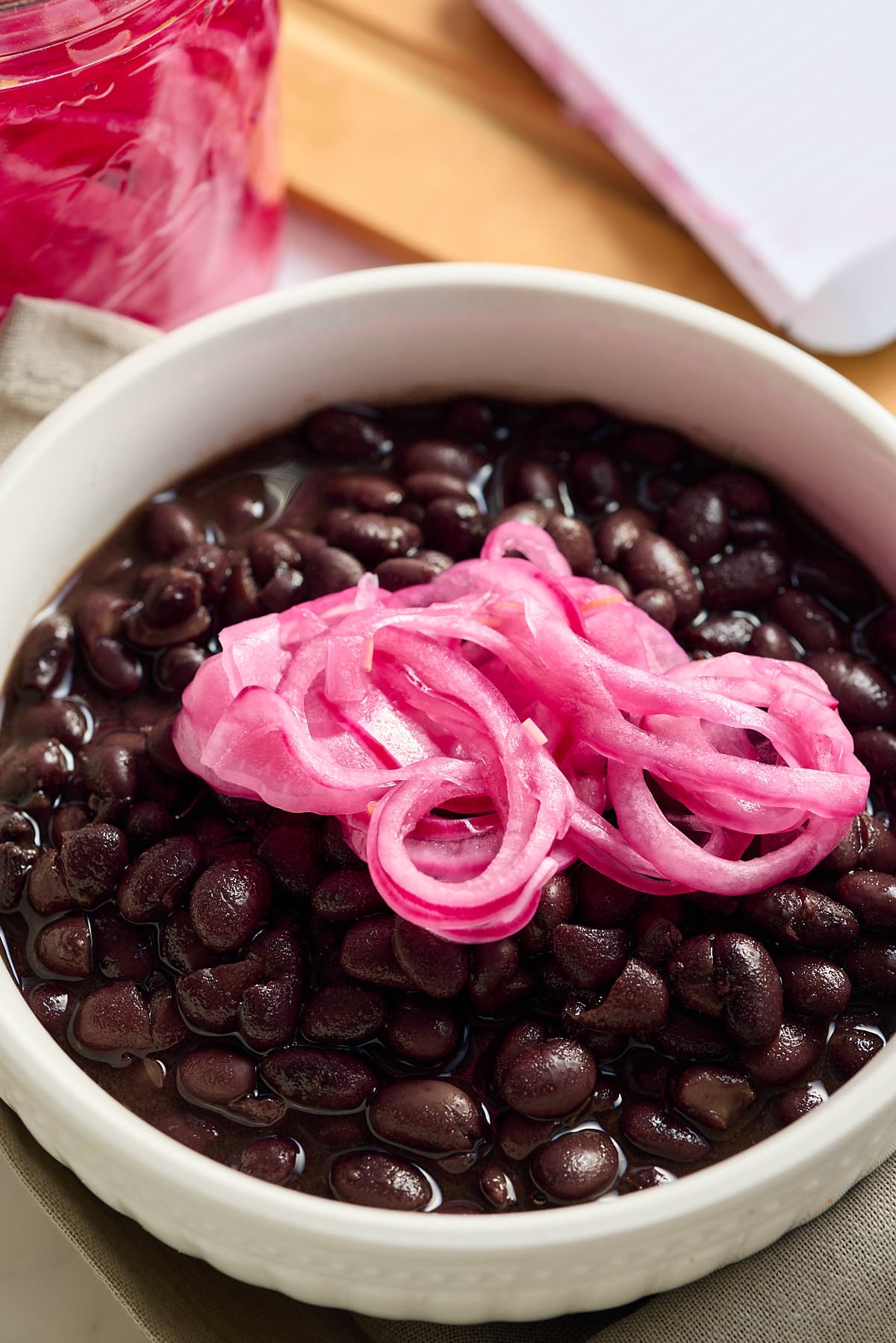 quick pickled red onions on top of a bowl of black beans