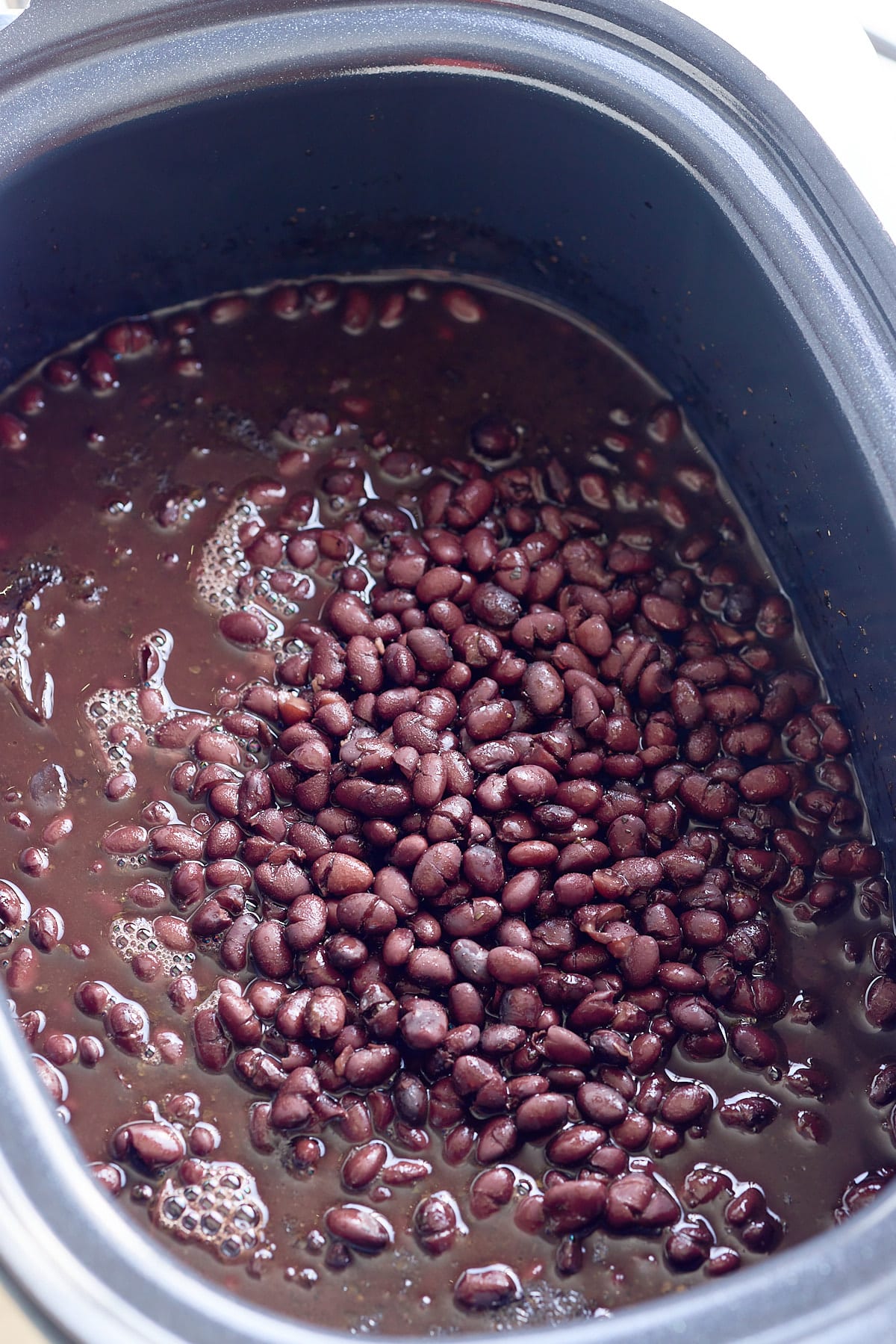 Freshly cooked black beans in the slow cooker with extra ingredients removed.