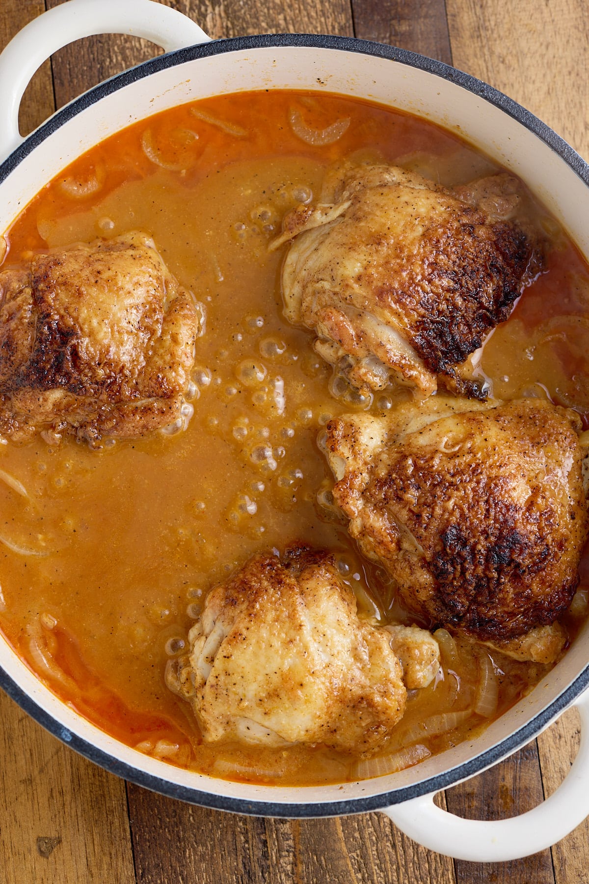 Dutch oven with sauteed chicken thighs, seasoned flour, onions and stock