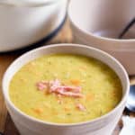 A bowl served with split pea soup topped with bits of ham.