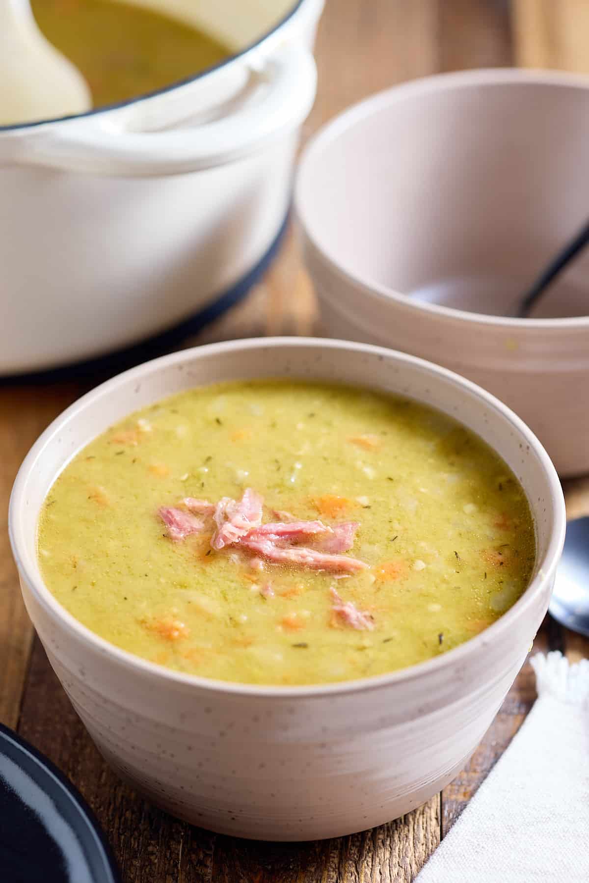 A bowl served with split pea soup topped with bits of ham.