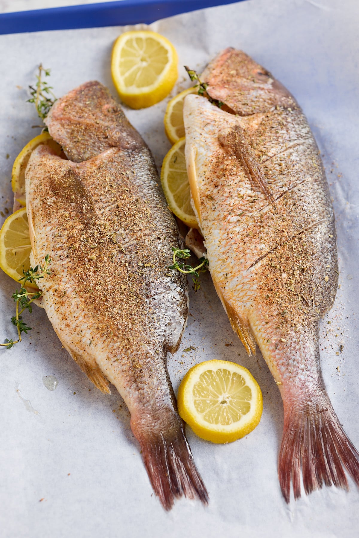 2 whole fish seasoned and set onto parchment paper stuffed with fresh thyme and lemon slices