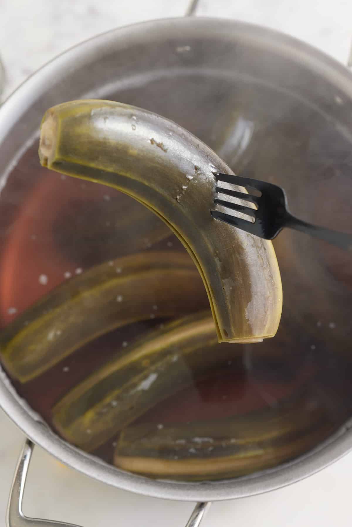 boiled green banana after being cooked, being picked up with fork