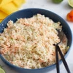 A bowl of Jamaican coleslaw with serving spoons.