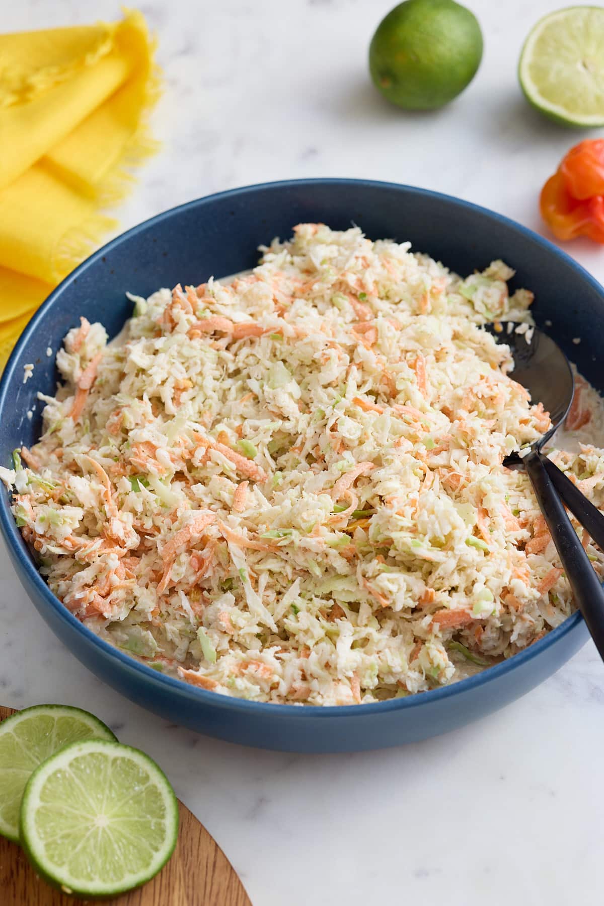 A bowl of Jamaican coleslaw with serving spoons.