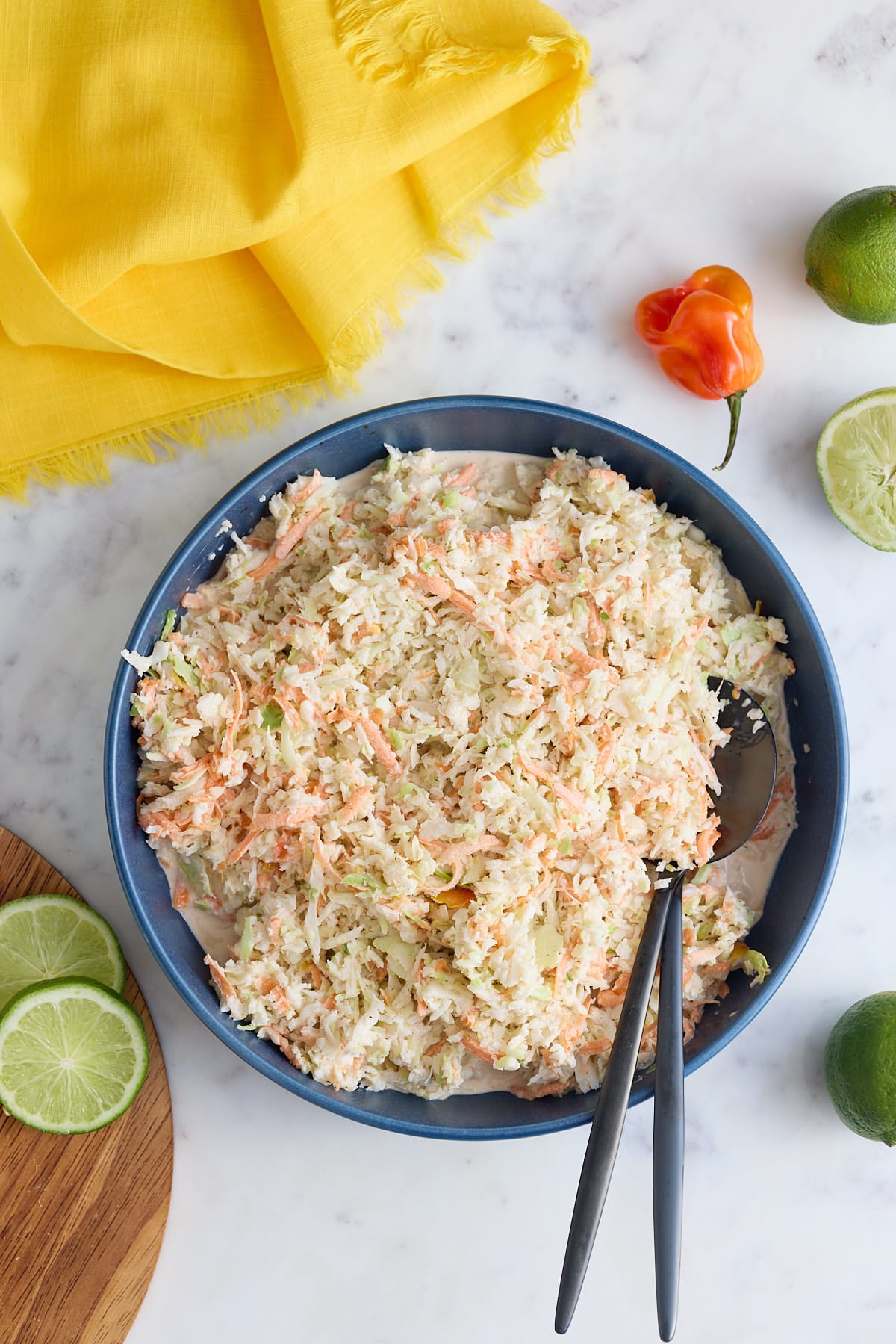 A bowl of Jamaican coleslaw with serving spoons.