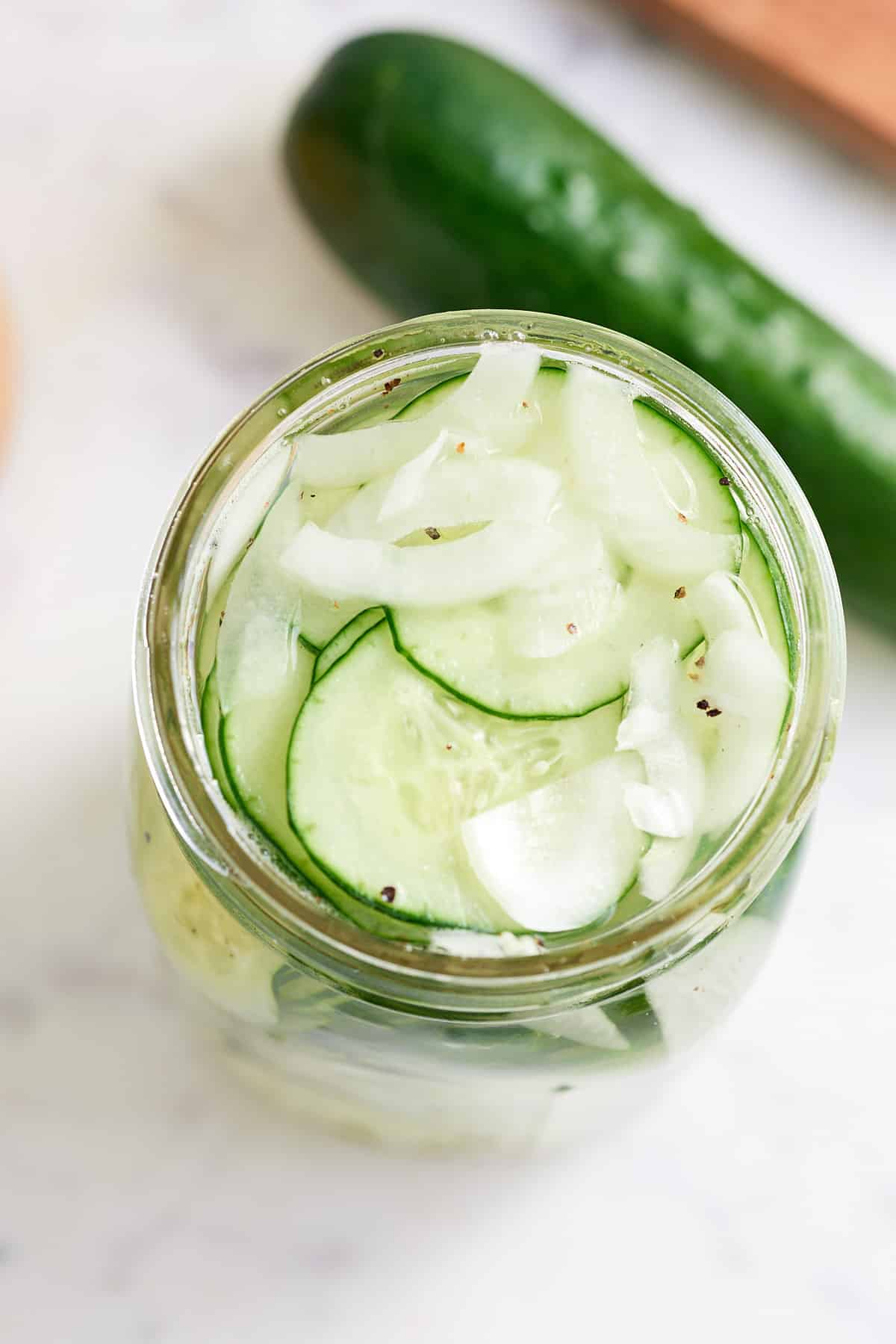 top down image of a glass jar filled with cucumber and onion pickles
