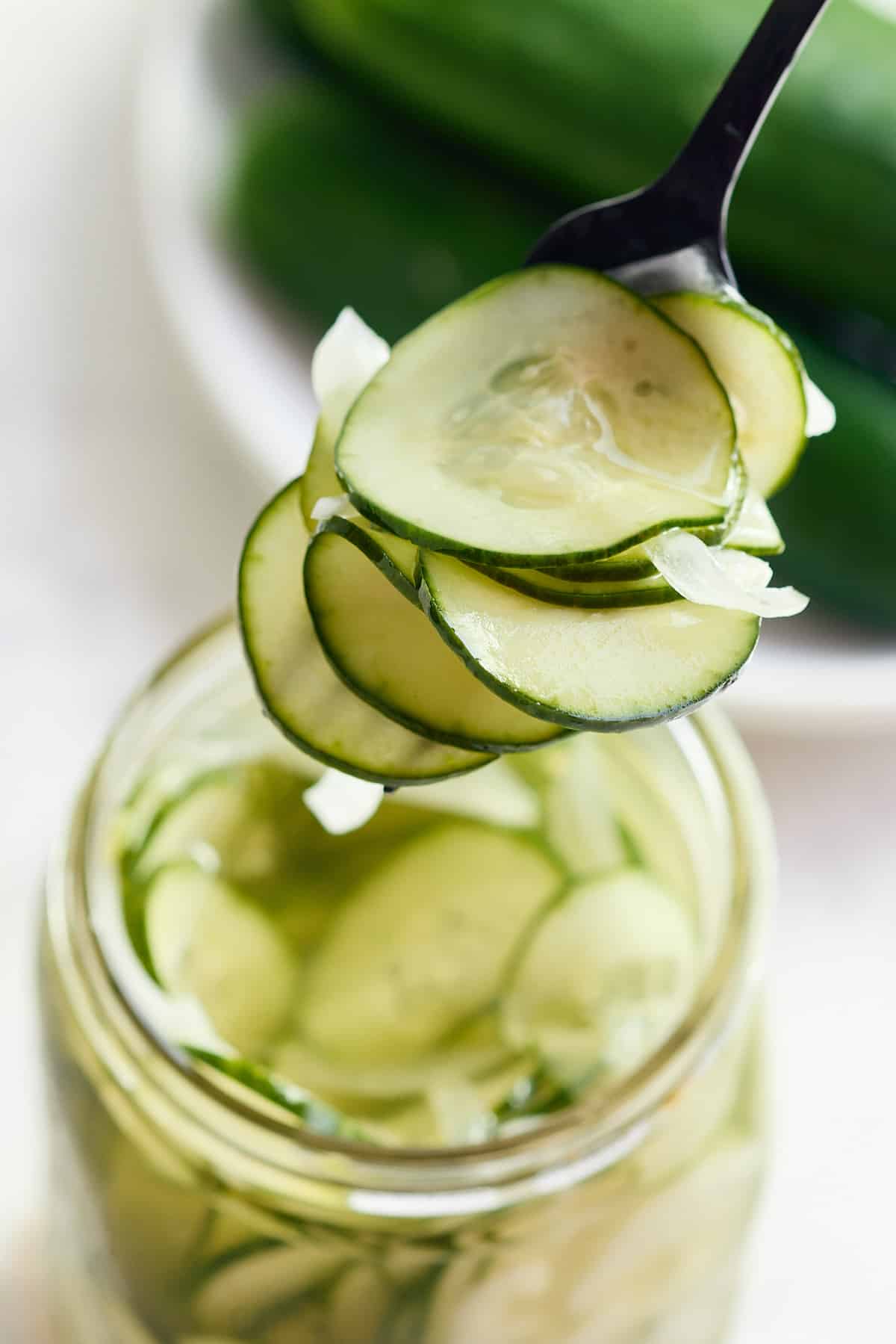 mason jar filled with pickles and a fork filled with cucumber and onion pickle