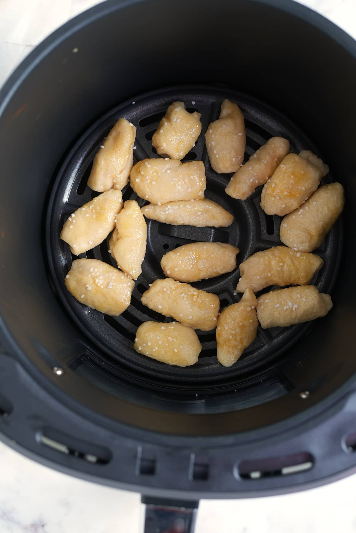 an air fryer basket filled with cooked balls of pizza dough