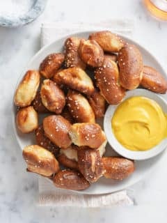 a top down image of a white bowl piled with air fried pretzel bites and a bowl of mustard dipping sauce