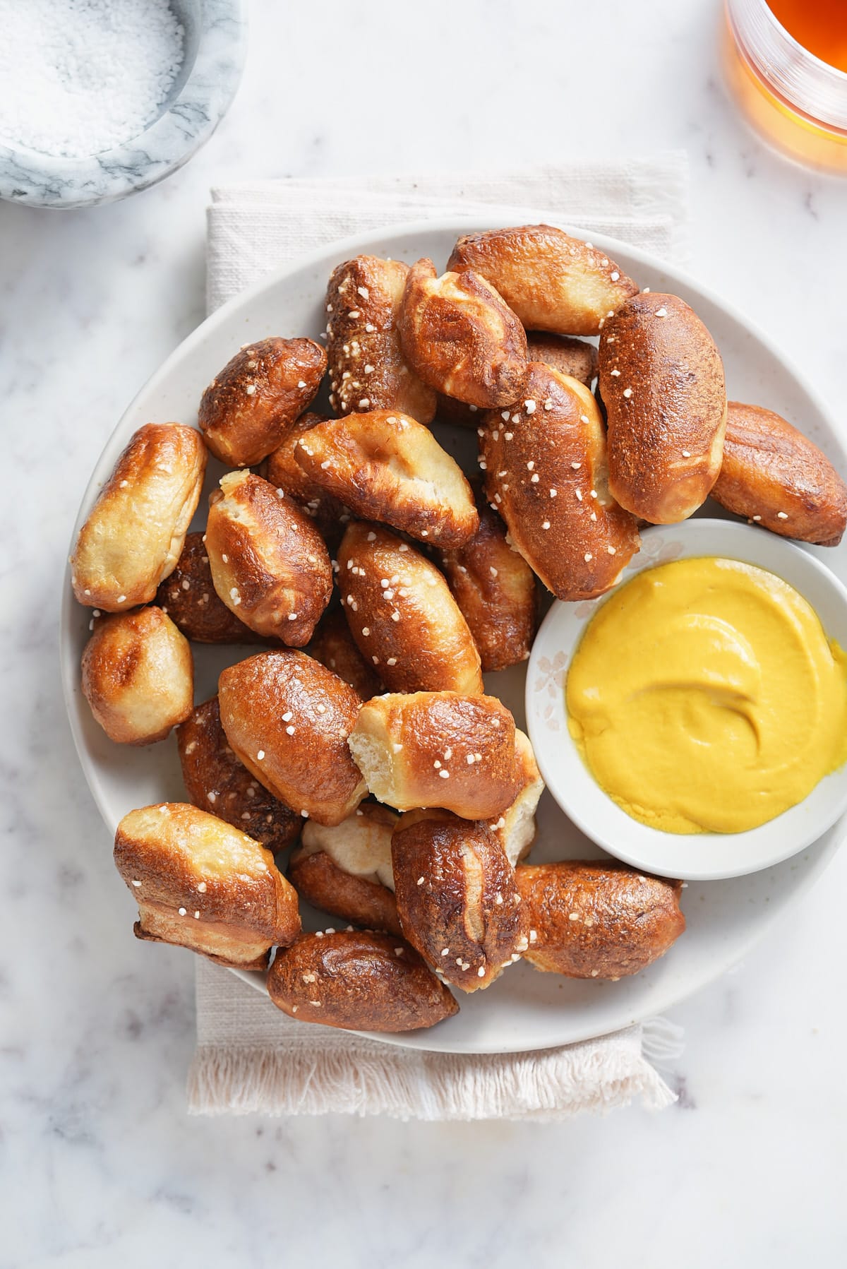 a top down image of a white bowl piled with air fried pretzel bites and a bowl of mustard dipping sauce