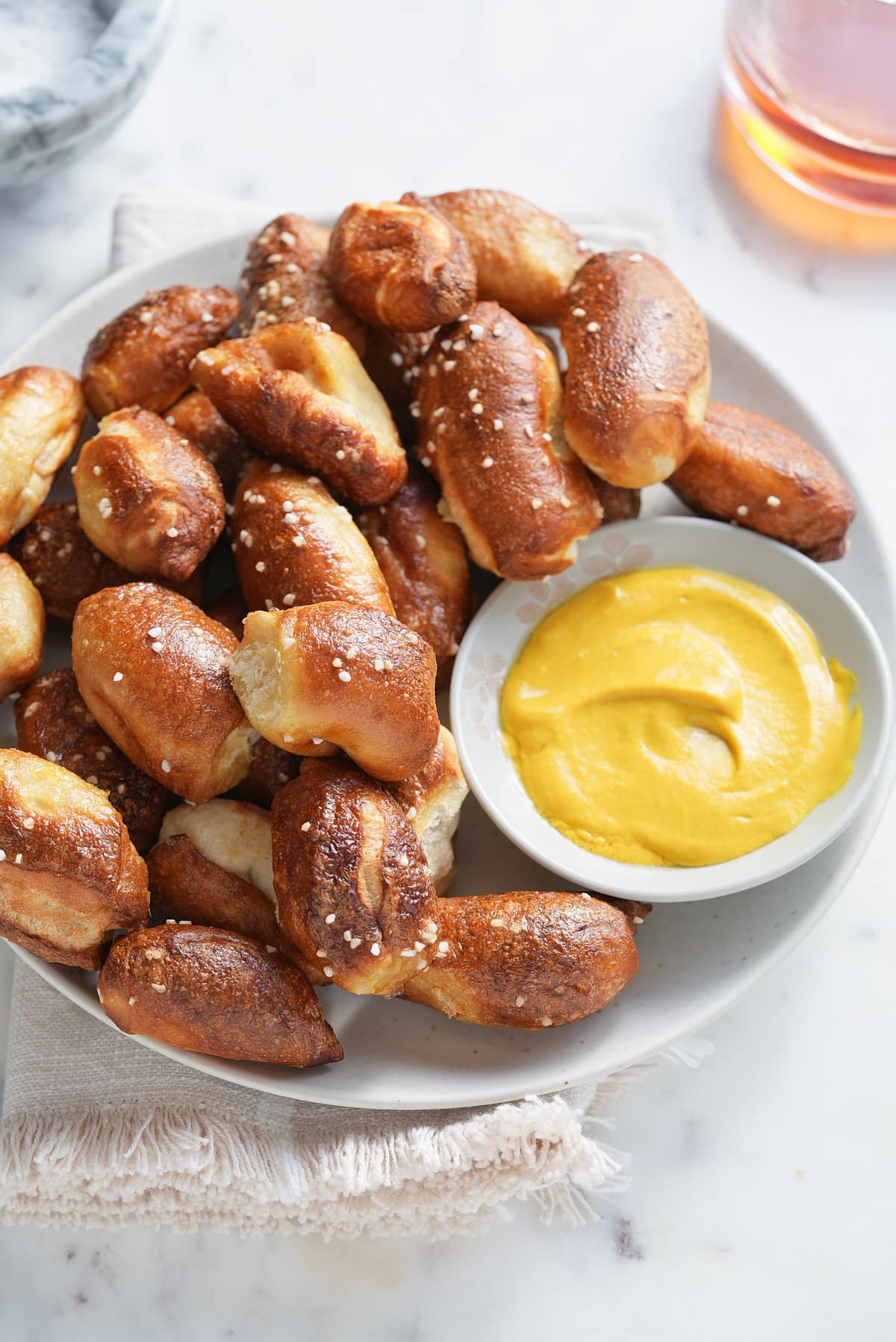 a white bowl piled with air fried pretzel bites and a bowl of mustard dipping sauce