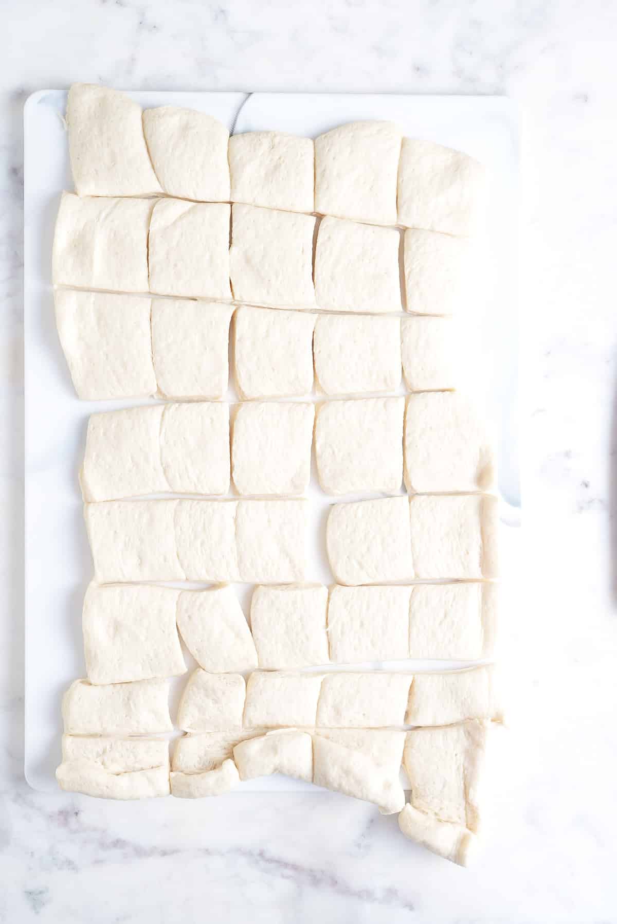 pizza dough on a chopping board cut into bite sized pieces