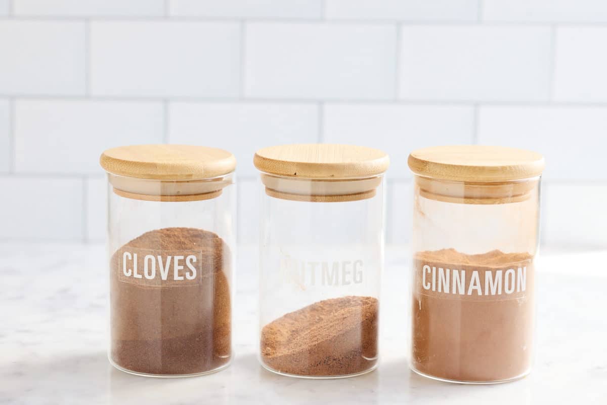 ground cinnamon, cloves and nutmeg in spice containers.