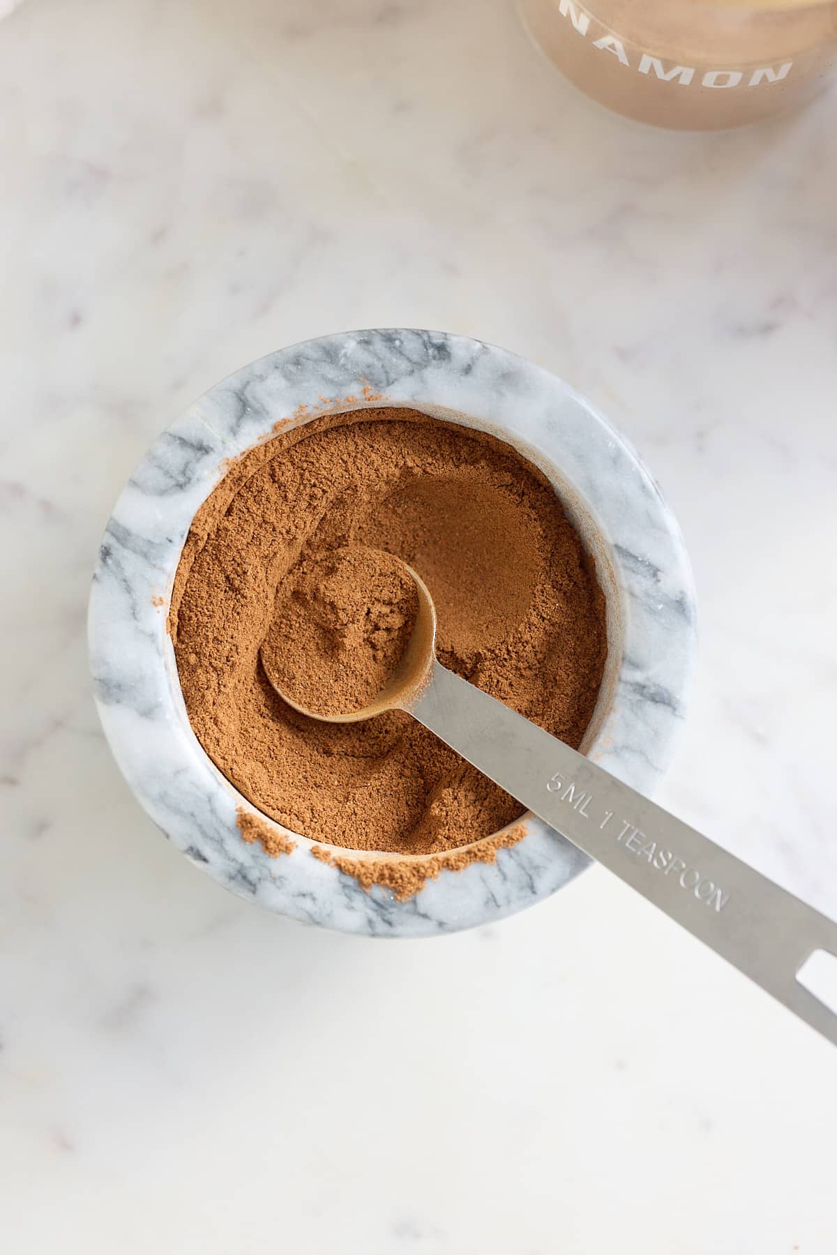 spice ingredients mixed together in a mortar bowl with a measuring spoon.