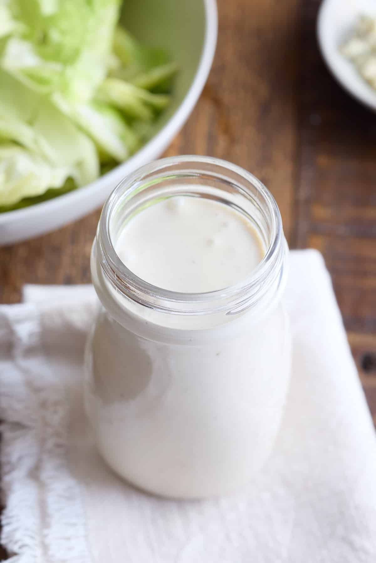 glass jar filled with blue cheese dressing set on a white linen napkin