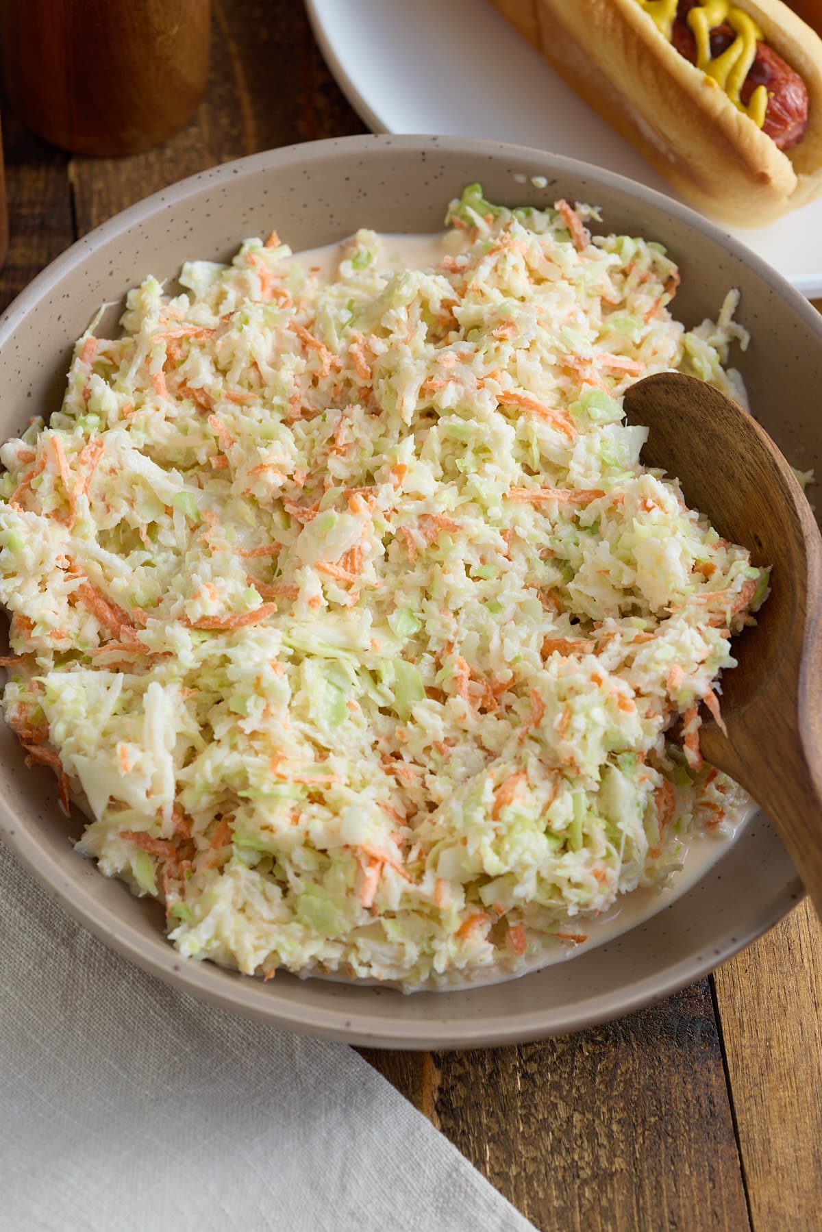 Coleslaw in a serving bowl with a wooden spoon.