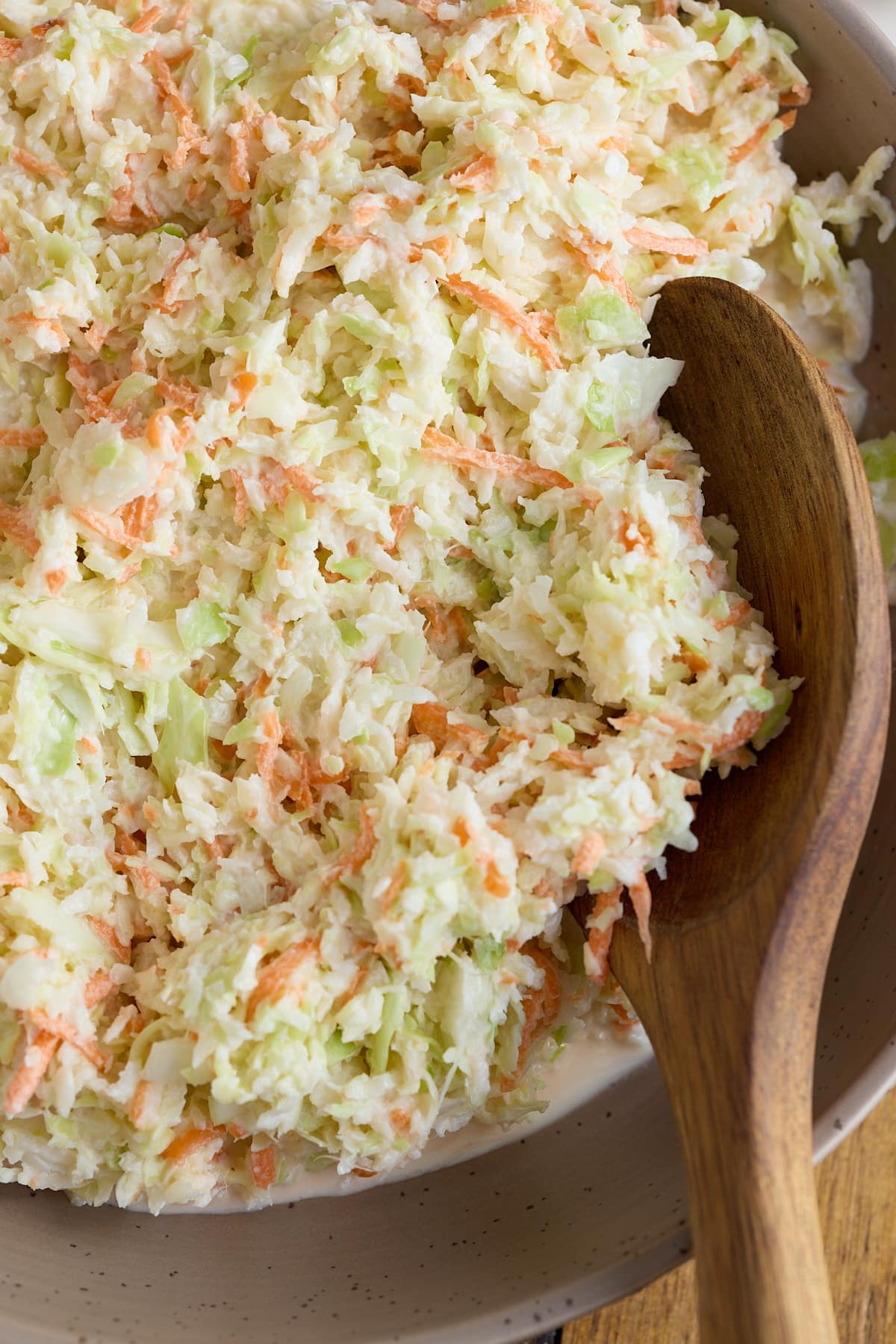 Coleslaw in a serving bowl with a wooden spoon.