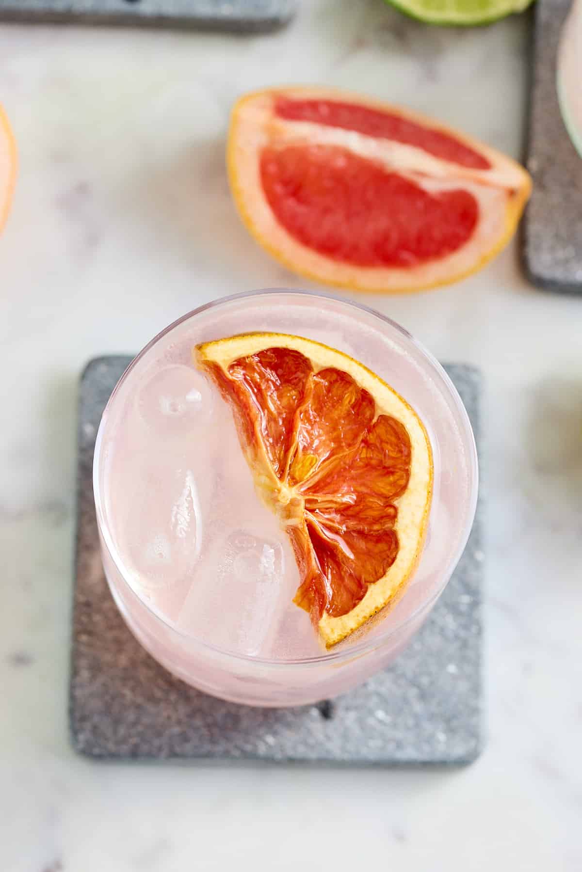 top down image of a glass of paloma cocktail with a garnish of sliced ruby grapefruit