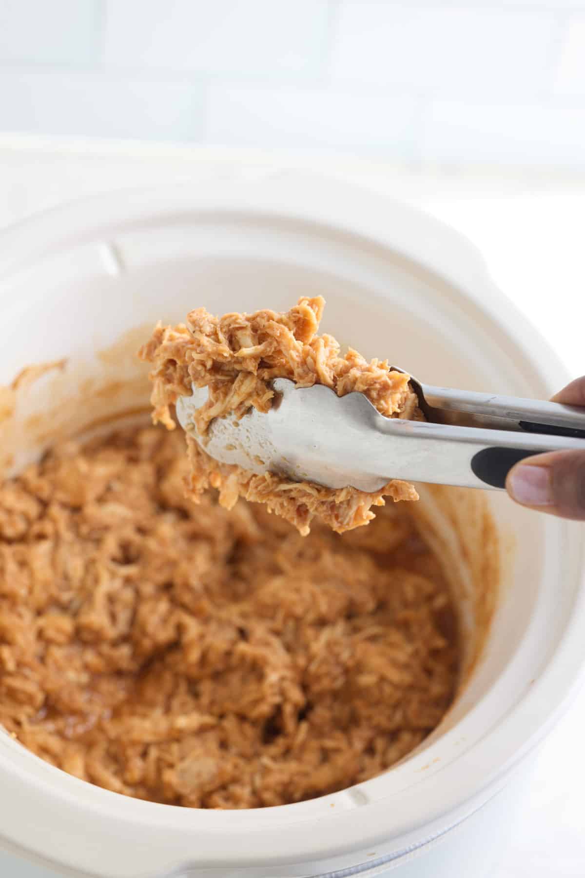 tongs grabbing bbq chicken.