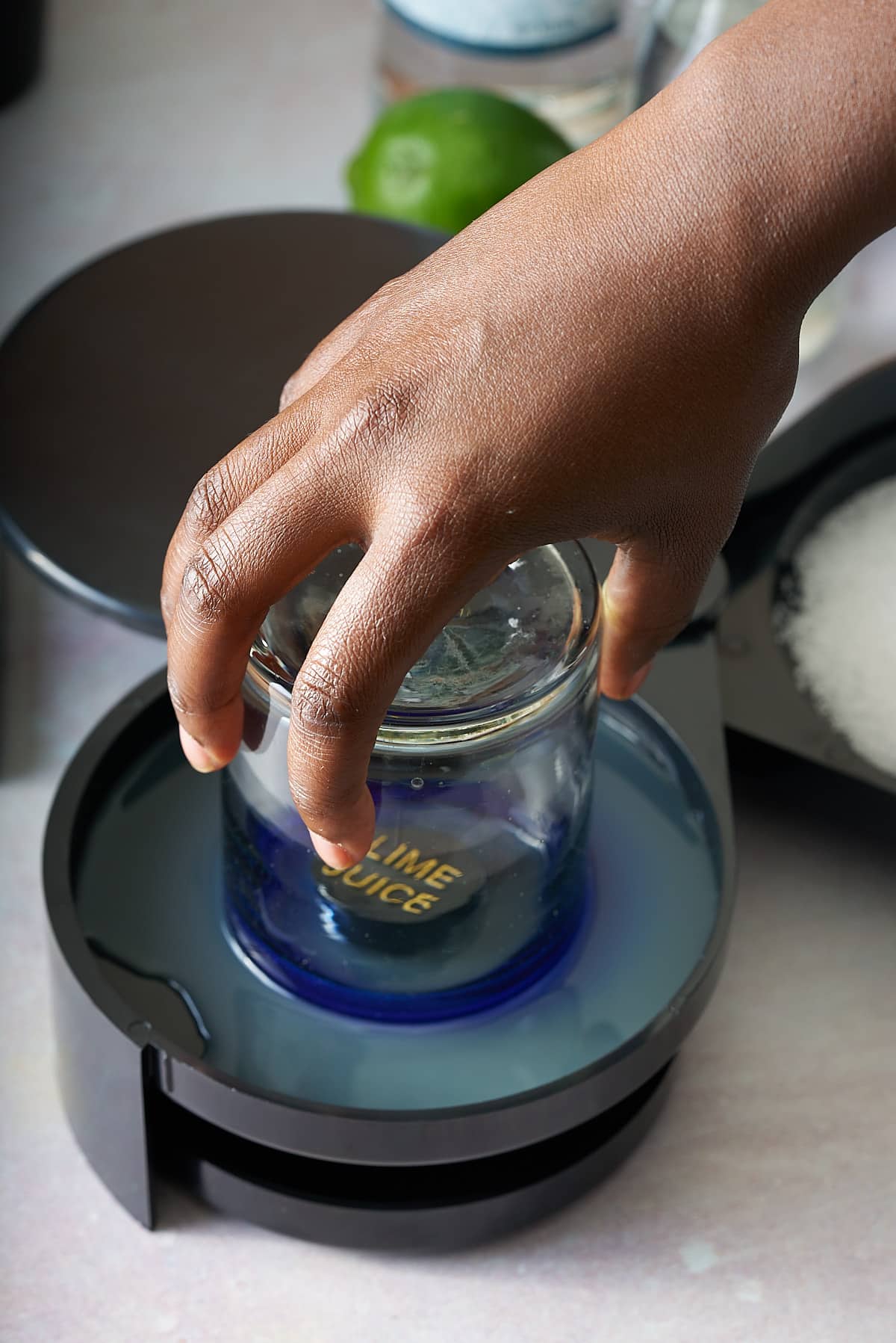 the rim of a glass being dipped into a shallow black dish filled with lime juice