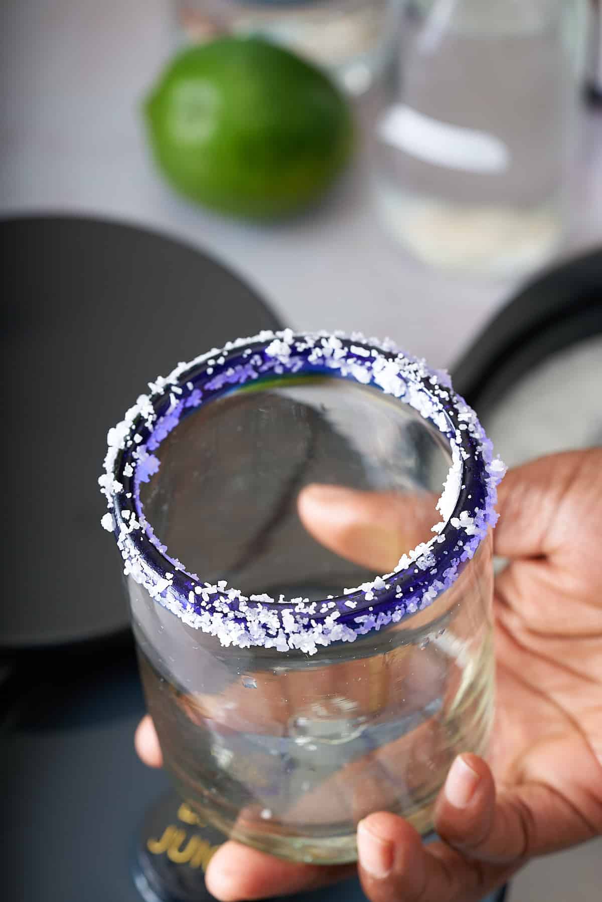 a hand holding a glass with a salt crusted rim