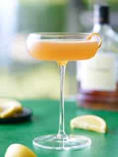 coupe glass filled with Hennessy sidecar cocktail and garnished with a strip of orange peel