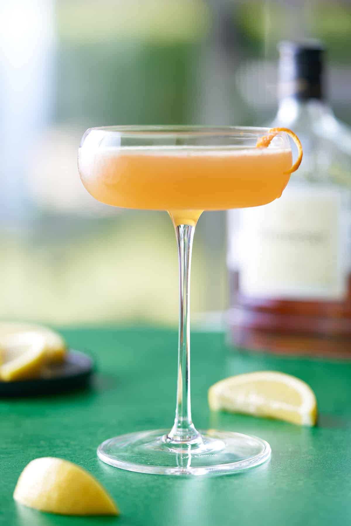 coupe glass filled with Hennessy sidecar cocktail and garnished with a strip of orange peel