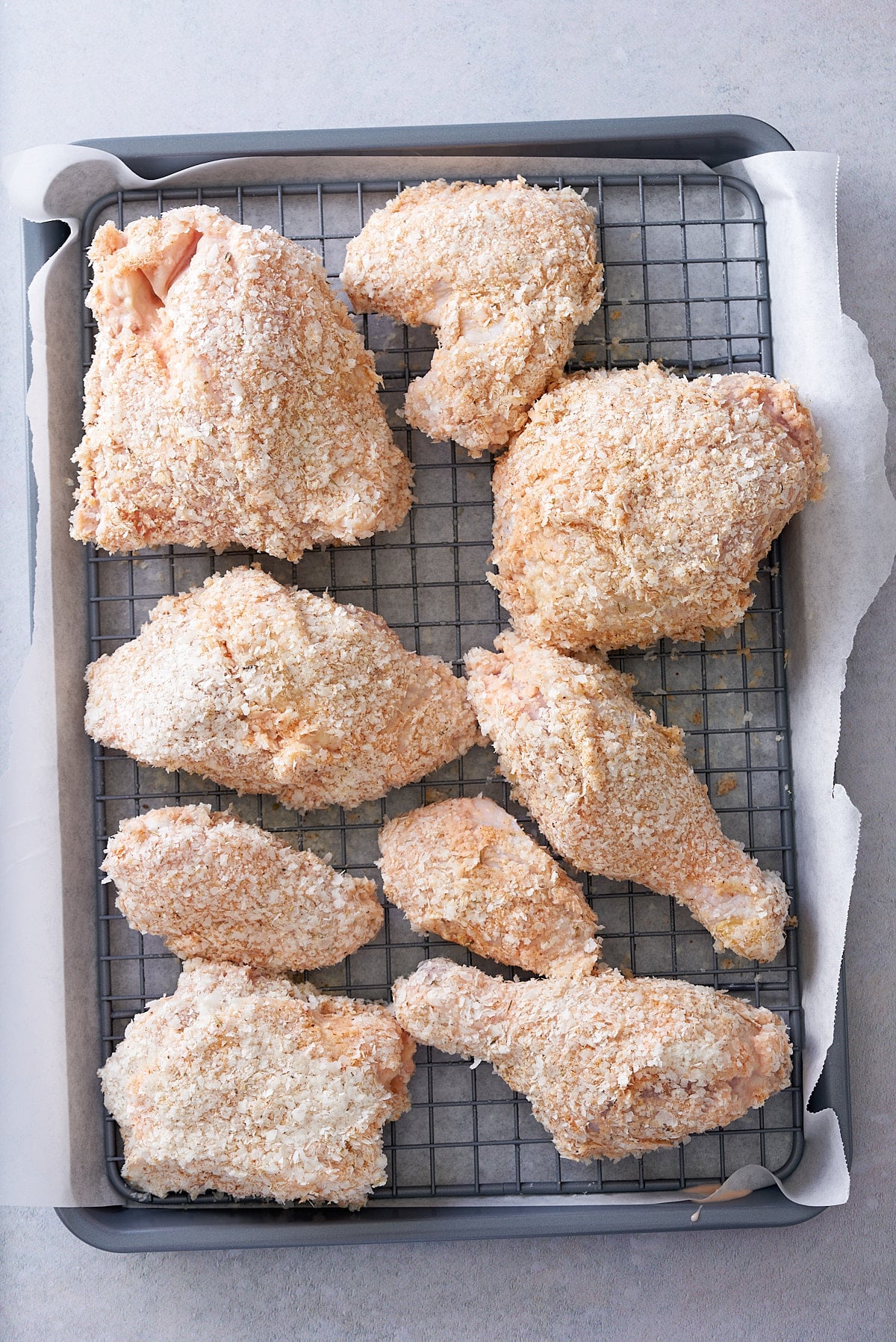 Wire rack set into a baking tray with pieces of crumbed chicken on top.