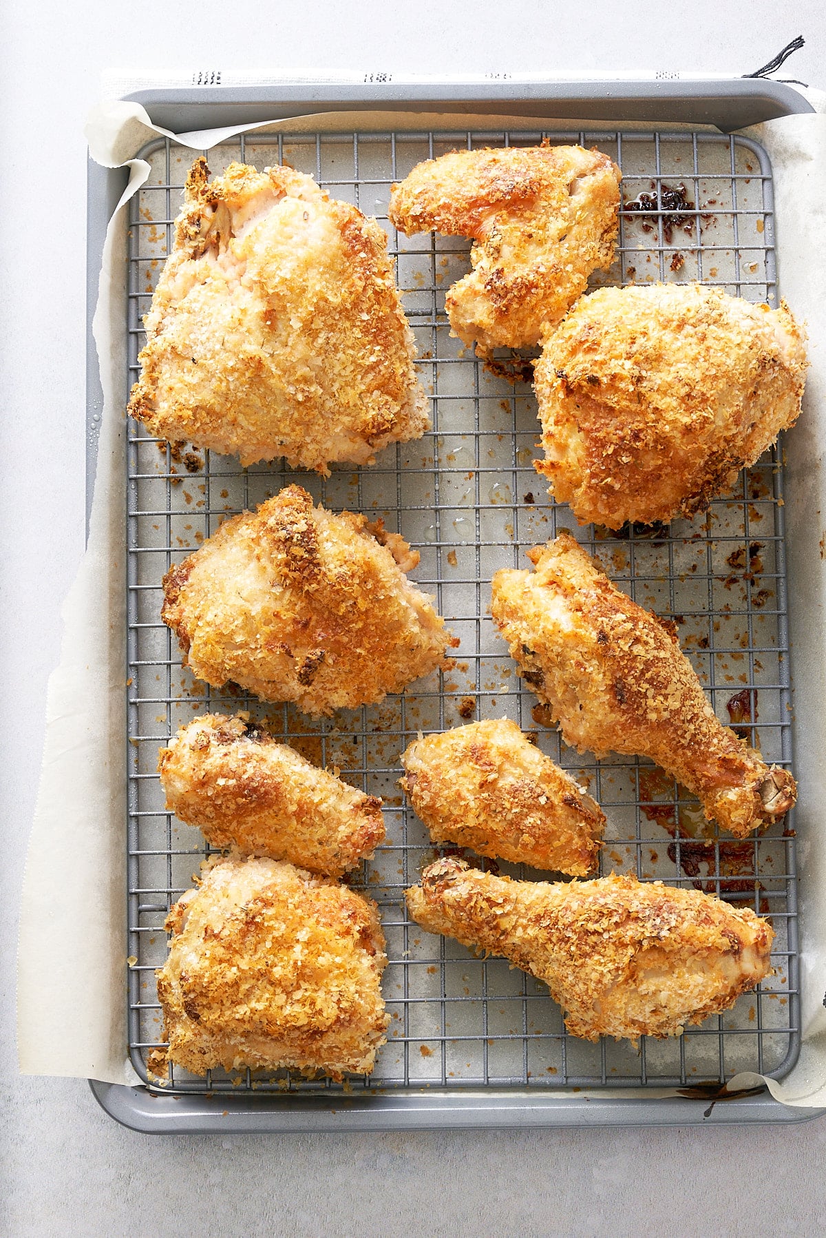 Wire rack set into a baking tray with pieces of crispy cooked chicken on top.