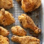 Wire rack set into a baking tray with pieces of crispy cooked chicken on top.