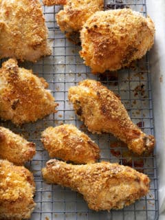 Wire rack set into a baking tray with pieces of crispy cooked chicken on top.