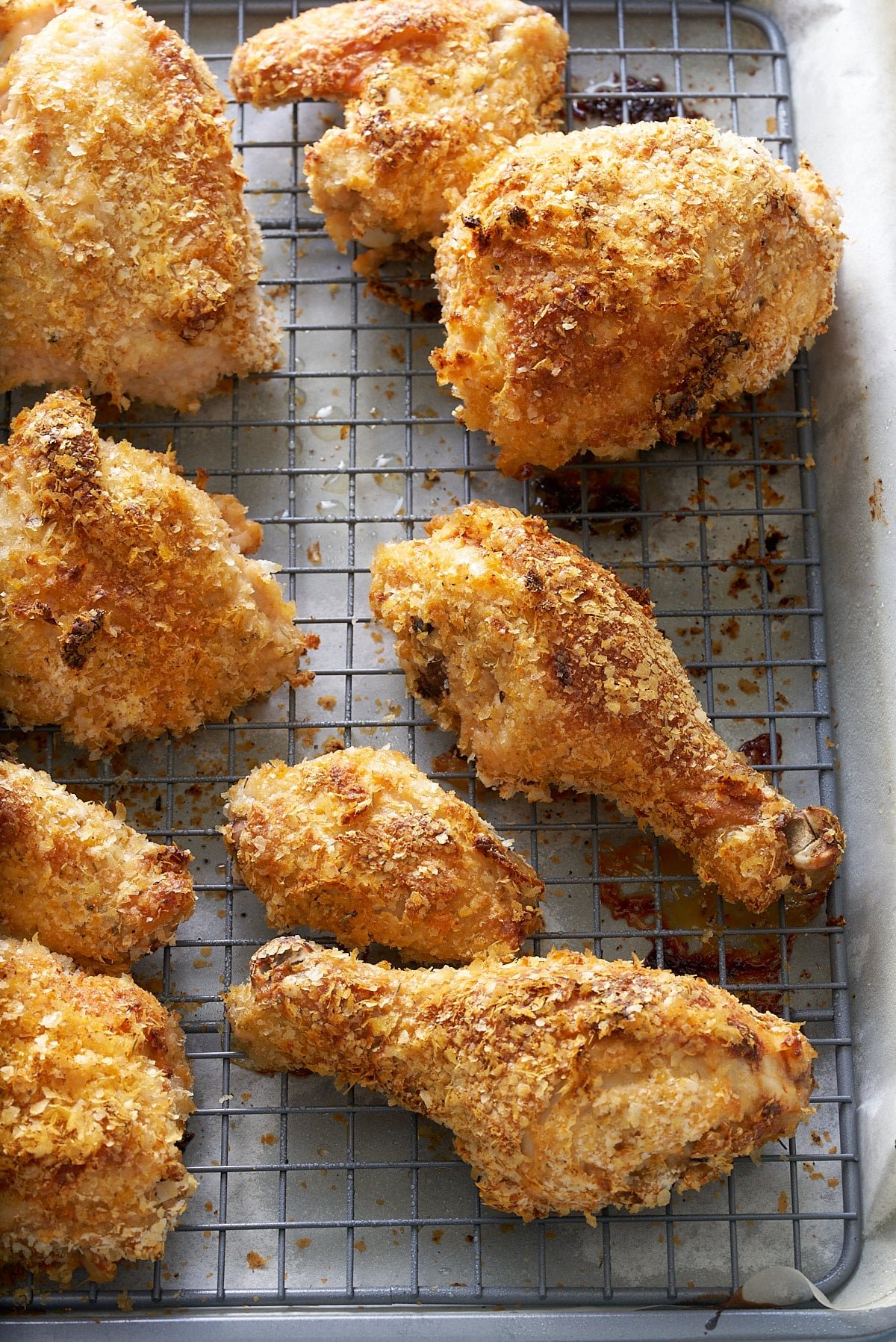 Wire rack set into a baking tray with pieces of crispy cooked chicken on top.