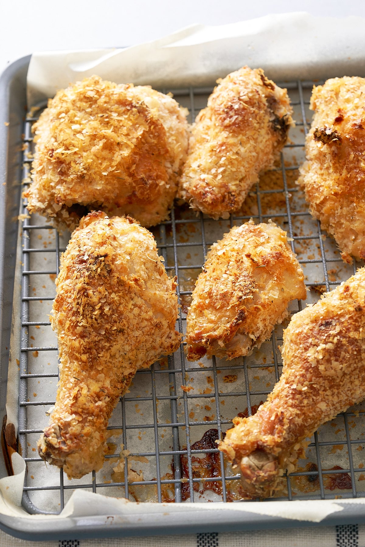 Wire rack set into a baking tray with pieces of crispy cooked chicken on top.