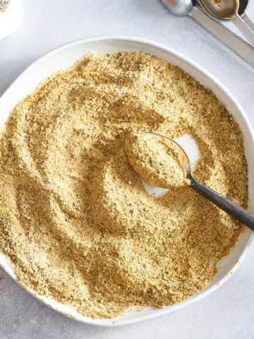Scooping the adobo seasoning spice with a spoon.